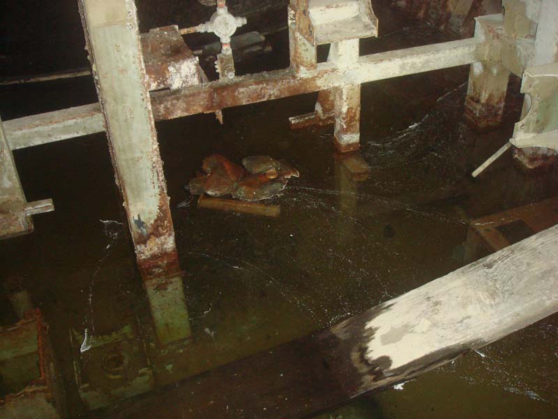 Dirty water, debris and rusty steel framework in the fuel storage area.