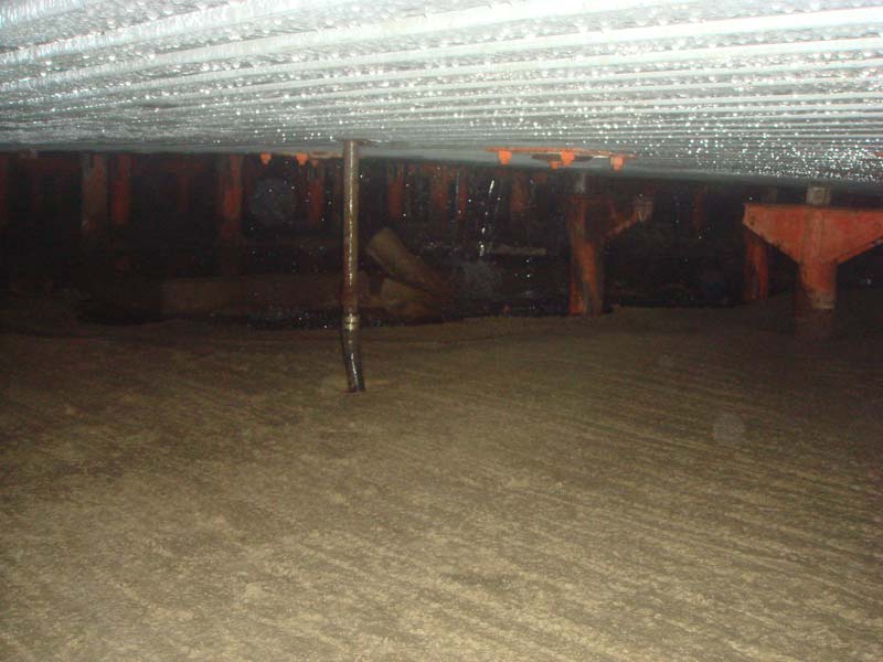 The view at the lowest level beneath the power house showing the silt collected there and the constant dripping of water from above. In the distance you can see more pedestals from the missing spring beams and a pipe which I believe was to one of the wells supplying the complex.
