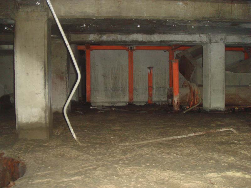 A sump well (hole at left) and large pipes and other structures in the background.