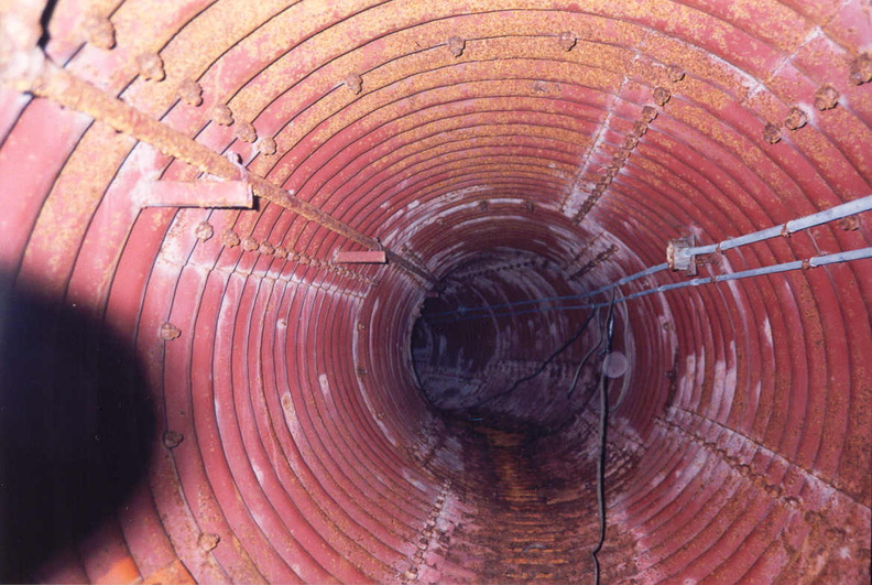 Launcher Air Filtration Facility at Lowry 724-C looking down the tunnel toward a shallow corner where it continues on to the filtration facility and supply fan. Note the evidence of standing water in this area. Behind this view is the tunnel leading to launchers 2 and 3 and their respective blast valves in the ceiling of blast lock #1. Taken: Circa 2002 Source: Myself tunnel-2-lafa.jpg